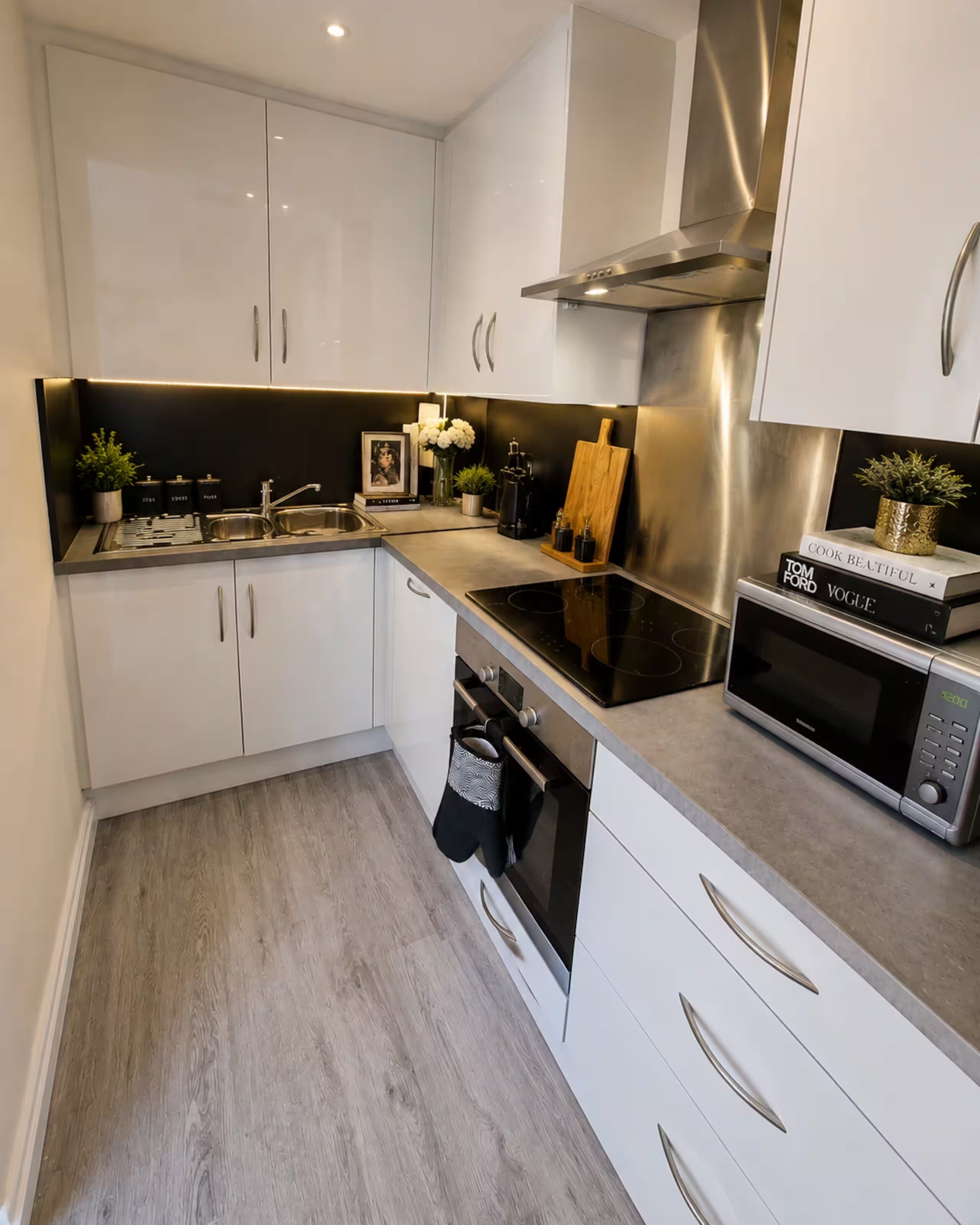 A modern kitchen with white cabinets, stainless steel appliances, and a wooden cutting board.