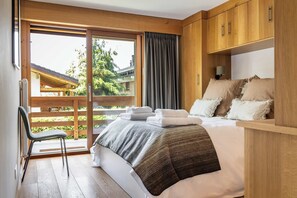 Ein Schlafzimmer mit Bett, Stuhl, Fenster und Blick ins Freie.