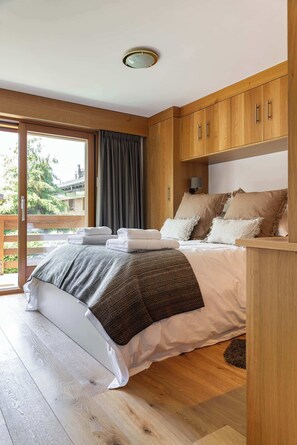 Ein Schlafzimmer mit einem großen Bett, einem Holzkopfteil und einer Schiebetür zu einem Außenbereich.
