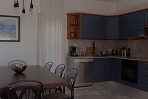 Une cuisine moderne avec des meubles bleus, un lave-vaisselle et un coin repas comprenant une table et des chaises.