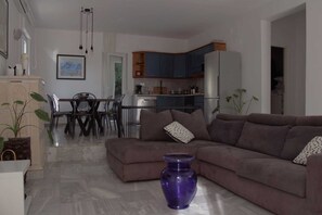A living room with a sofa, a dining table with chairs, a kitchen area with cabinets and appliances, and a purple vase on the floor. - Villa Bamboo - Green villa with heated pool (Duće)