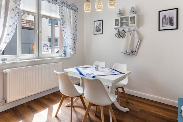 A dining area with a table, chairs, and a window with curtains.