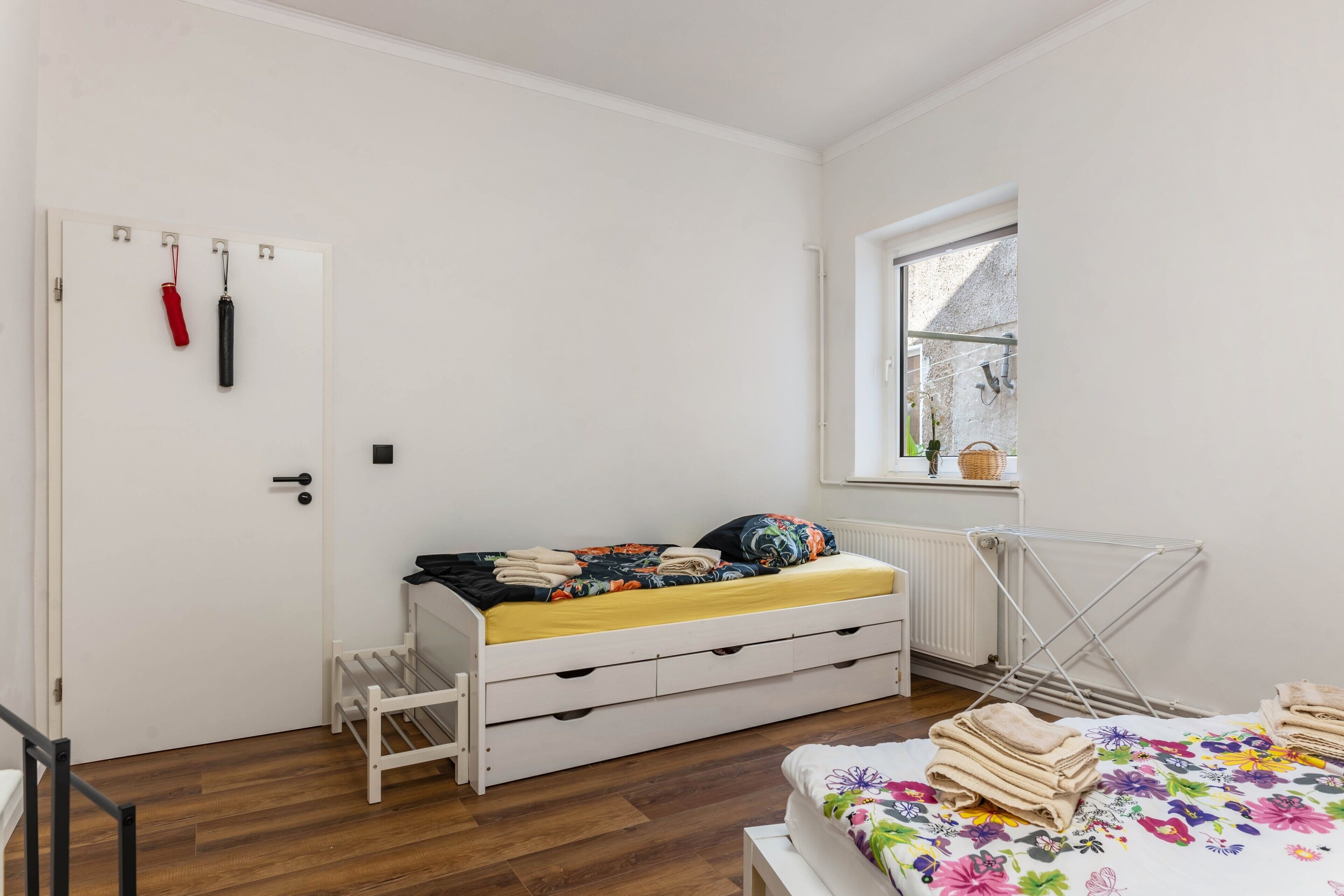 Une chambre à coucher avec un lit, un radiateur, une fenêtre et un étendoir.