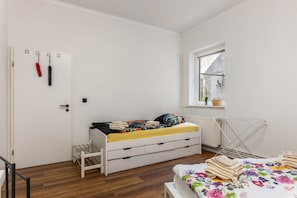 A bedroom with a bed, a radiator, a window, and a drying rack.