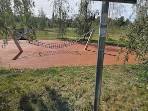 A playground with a rope net, a metal pole, and a red surface.