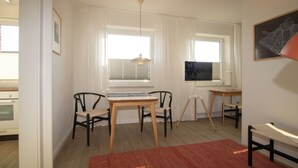 Una habitació amb escriptori, dues cadires, una catifa vermella i una finestra amb persianes.