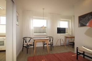 A room with a desk, two chairs, a red rug, and a window with blinds. - Beachfront vacation rental in Hörnum, right next to the golf course. (Hörnum (Sylt))