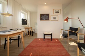 A modern living room with a dining area, a red carpet, and artwork on the wall. - Beachfront vacation rental in Hörnum, right next to the golf course. (Hörnum (Sylt))
