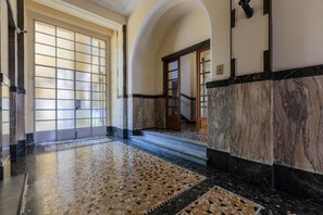 A hallway with a tiled floor, a door with frosted glass panels, and a staircase with a marble finish. - Galliari Comfort Home by Wonderful Italy (Turin)