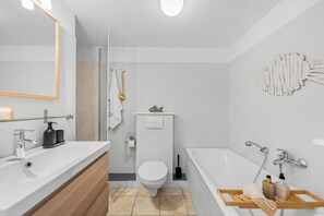 A modern bathroom with a white sink, a toilet, a bathtub, and a shower. - Nordstern Vacation Rental with Ocean Views and Two Balconies on Schönberg Beach (Schönberg (Holstein))