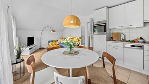 A modern kitchen with white cabinets, a dining table with chairs, and a hanging light fixture. - Nordstern Vacation Rental with Ocean Views and Two Balconies on Schönberg Beach (Schönberg (Holstein))