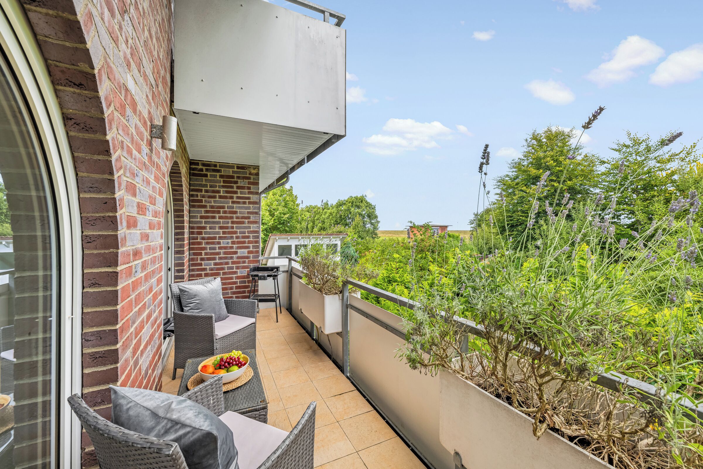 Un balcón con mobiliario exterior, una parrilla y vistas a zonas verdes.