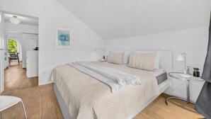 A bedroom with a bed, bedside tables, a lamp, and a painting on the wall. - Nordstern Vacation Rental with Ocean Views and Two Balconies on Schönberg Beach (Schönberg (Holstein))