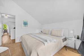 Ein Schlafzimmer mit einem Bett, Nachttischen, einer Lampe und einem Bild an der Wand.