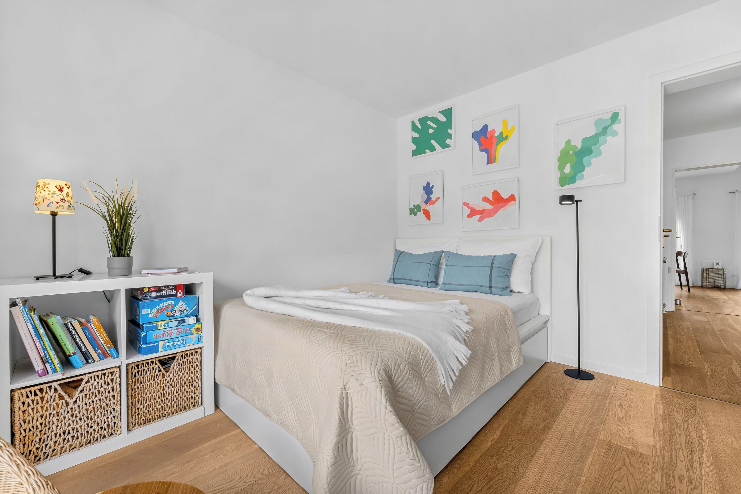 Ein modernes Schlafzimmer mit einem Bett, einem Bücherregal und Wandbildern.