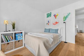 Een moderne slaapkamer met een bed, een boekenkast en decoratieve wandkunst.