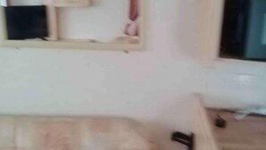 Ein Zimmer mit einem Bett, einem Wandregal und einem Fenster.