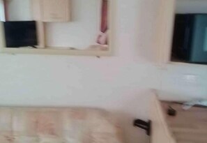 A room with a bed, a wall-mounted shelf, and a window. - Caravan - Sleeps 4 - Parking (Eyemouth)