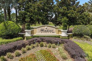 A landscaped entrance with a sign reading 'Windsor Hills 2600'. - Cozy 2BR Mickey condo in Windsor Hills with view (Kissimmee)