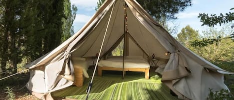 Una tenda a forma di cupola con un letto all'interno, circondata da alberi.