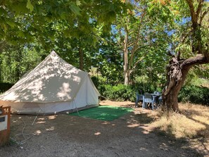 A tent set up in a forested area with a green mat in front. - SLOW LIFE CAMPING (VENTA DEL MORO)