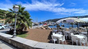 Een jachthaven met boten, een restaurant met terras en een helderblauwe lucht.