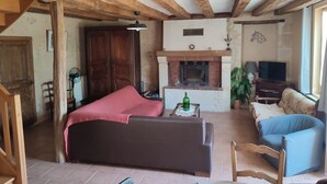 A cozy living room with a fireplace, a sofa, a television, and a dining area.