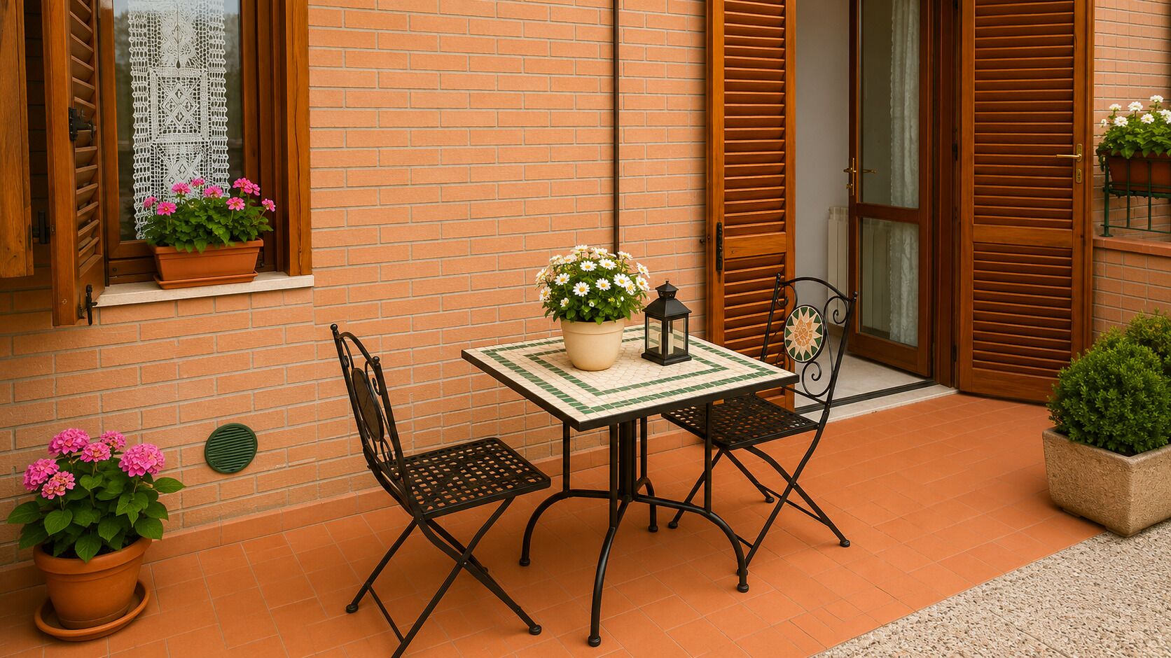 A patio with a table and two chairs, a potted plant, and a brick wall.