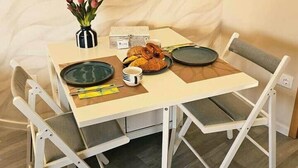 Een eettafel met stoelen, een bloevas en een bord eten.