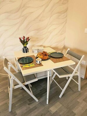 A dining table with chairs, a vase of flowers, and a plate of food. - BO - SilvaBlau Apartment Hévíz (Hévíz)