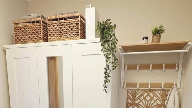 Een kamer met een kledingkast, een bankje met een plant en een decoratief roomdivider.