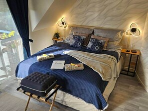 A bedroom with a bed, bedside tables, a bench, and a view of the outdoors. - BO - SilvaBlau Apartment Hévíz (Hévíz)