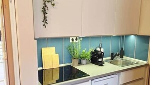 Een kleine keuken met een ingebouwde kookplaat, een spoelbak en witte keukenkastjes.