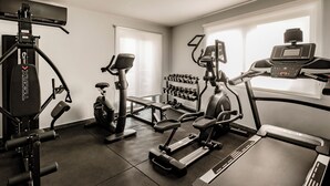 Un gimnasio con diferentes equipos de ejercicio, incluyendo cintas de correr, una bicicleta estática y máquinas de pesas.