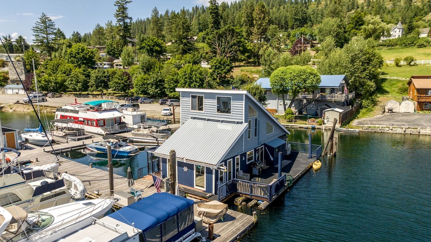 A waterfront property with a dock, boats, and a house with a large deck.