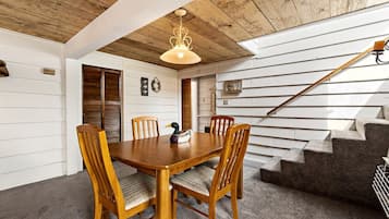 A dining area with a wooden table and chairs, a duck figurine, and a staircase with a wooden handrail.