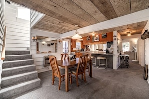 A spacious kitchen with wooden cabinets, a dining area with a table and chairs, and a staircase leading to an upper level.