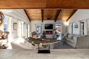 A cozy living room with a wooden ceiling, a large fish sculpture, a sofa, and a television.
