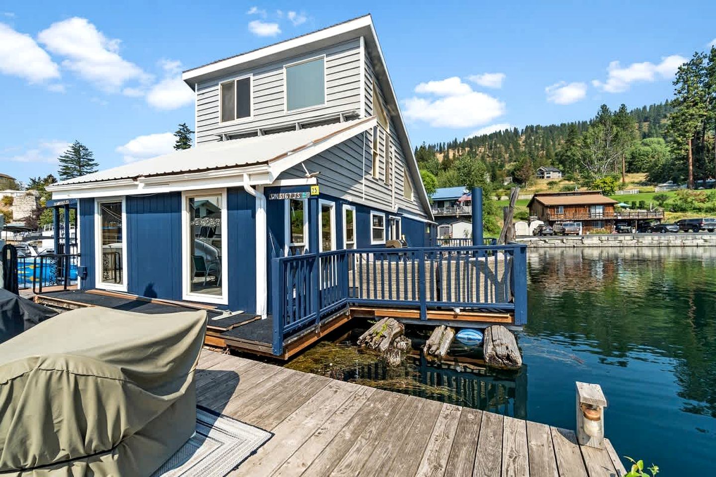 Ein Hausboot mit Deck, Fenstern und einer anlegenden Mole.