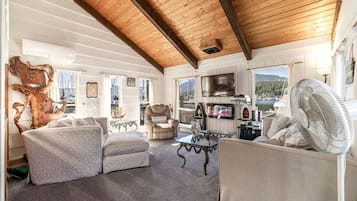 A cozy living room with a fireplace, comfortable seating, and a view of the outdoors.