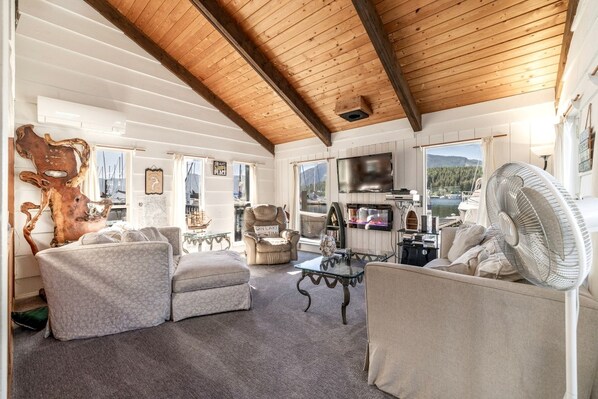 A cozy living room with a fireplace, comfortable seating, and a view of the outdoors.