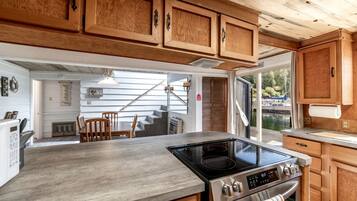 A modern kitchen with wooden cabinets, a large stove, and a dining area with a table and chairs.