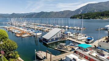 Eine Marina mit vertäuten Booten, ein Gebäude mit Satteldach und Berge im Hintergrund.