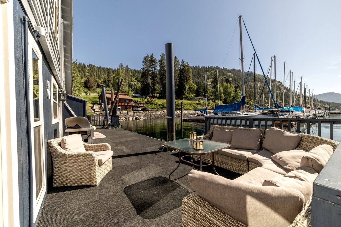 A balcony with wicker furniture, a table, and a view of a marina with boats.