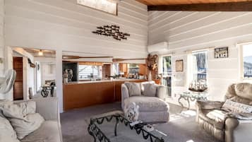 Un salon confortable avec un canapé, une table basse et une table à manger. Il y a également un coin cuisine avec un bar et une vue sur les bateaux à l'extérieur.