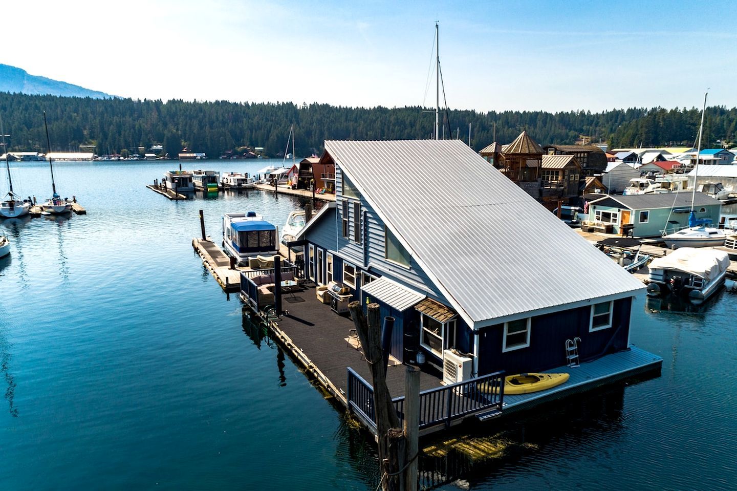 A waterfront property with a dock, boats, and a house with a metal roof.