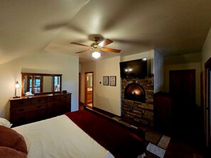 A bedroom with a bed, dresser, ceiling fan, fireplace, and a television. - Stylish Mountain Retreat with Game Room & Private Fire Pit in McCall, Idaho (McCall)