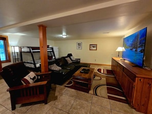 A living room with a sofa, armchairs, a coffee table, a TV, and a wooden cabinet. - Stylish Mountain Retreat with Game Room & Private Fire Pit in McCall, Idaho (McCall)