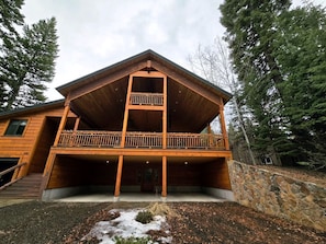 A two-story wooden cabin with a balcony on the upper floor, surrounded by trees. - Stylish Mountain Retreat with Game Room & Private Fire Pit in McCall, Idaho (McCall)