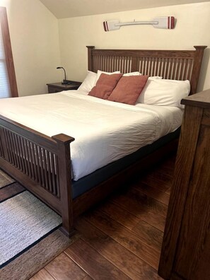 A wooden bed with a headboard, white bedding, and a brown pillow. - Stylish Mountain Retreat with Game Room & Private Fire Pit in McCall, Idaho (McCall)